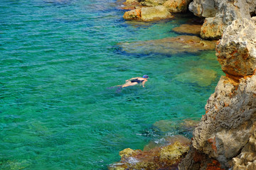View on the crystal sea water and unknown person swiming on Menorca.
