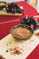 Zira rice lies in an oriental plate. dark rice lies on an oriental background, a golden tablecloth, a wooden cutting board next to basil.