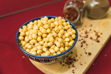 Preparation for cooking chickpeas and pilaf. Yellow chickpeas lie in an oriental plate on a wooden spice board.