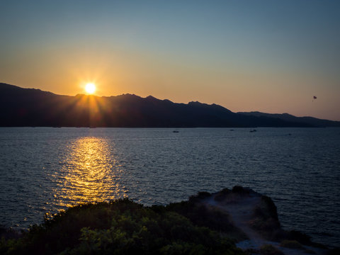 Sunset in Saint Florent (Corsica – France) – silhouette of a parasailing in background