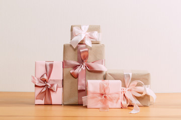 set of beautiful different gift boxes made by handmade with pink bows on a wooden table with a light background. flat lay