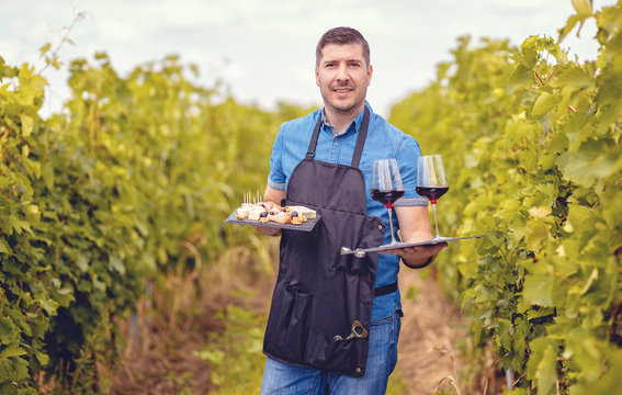 Man In Vineyard Welcoming Tourists With Red Wine And Selection Of Cheeses – Wine Tasting Tours Concept