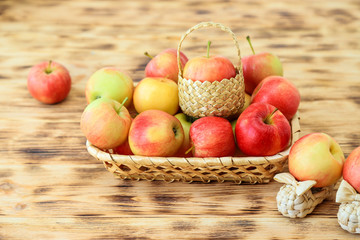 Red apples in a wicker plate on a wooden table. Wicker shoes and apples in a basket. Healthy food...
