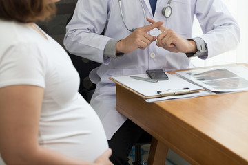 Doctor showing warning with hand sign and talking to the pregnant woman. Prohibition during...