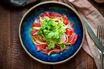 Tuna fillet ceviche with marinated, green, parsley, onion on blue plate. Fresh fish tartare