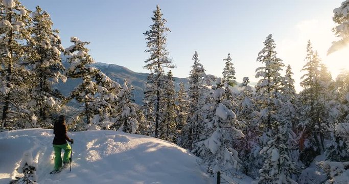Woman Snowshoeing In The Forest At Sunset