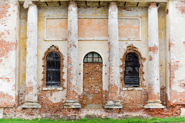 Fototapeta na wymiar wall of a dilapidated building of an old construction, the entrance to which is bricked up, and the windows are boarded up