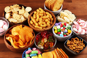 Salty snacks. Pretzels, chips, crackers and candy sweets on table