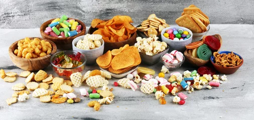 Poster Salty snacks. Pretzels, chips, crackers and candy sweets on table © beats_