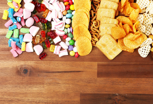 Salty snacks. Pretzels, chips, crackers and candy sweets on table