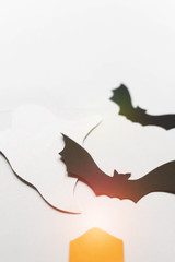 Halloween decorations with paper bats, candles and ghosts on white background. Halloween and decoration concept. Lens flare effect. Flat lay, top view, copy space