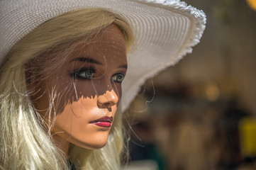 Portrait of a mannequin (display dummy) standing behind a shop window. Concept: Fashon and beauty