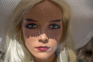 Portrait of a mannequin (display dummy) standing behind a shop window. Concept: Fashon and beauty