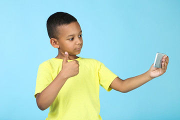 Cute american boy making selfie on mobile phone