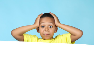 Cute american boy with blank board on blue background