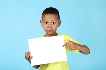 Cute american boy with blank board on blue background