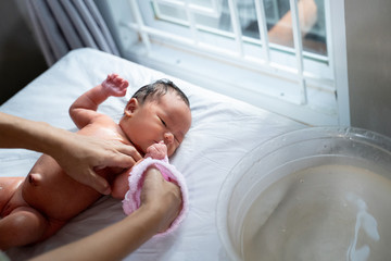 little daughter bath using wet towel with mother at home