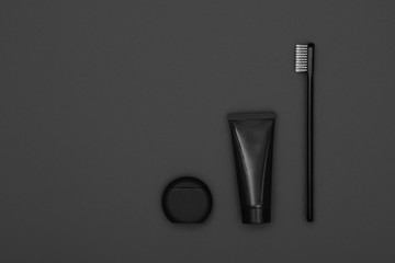 Black toothpaste and toothbrush over grey
