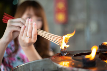 Beautiful Asian girl burning incense upon the incense altar in the Chinese temple.