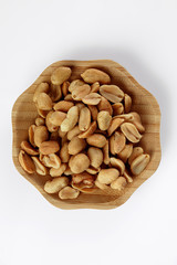 wood plate of salted peanuts isolated on white background. snack to beer