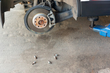 Wheel bolts lie on the asphalt next to the brake disc of the car.