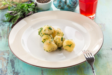 young boiled potatoes with dill in oil on white plate on blue wooden table