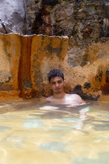 Hispanic man submerged in hot springs - man in natural pool relaxing -Latin in the natural spa -...