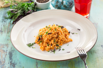 Bulgur with basil and squash and glass of berry drink on blue wooden table