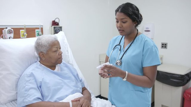 Nurse explains a flow meter to a patient in hospital patient room