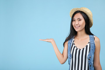 Beautiful young woman in straw hat on blue background