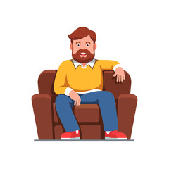 Smiling bearded man sitting on home arm chair
