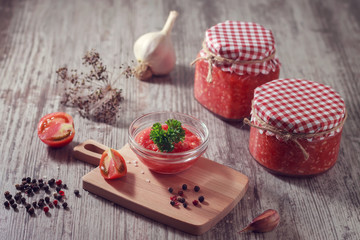 Homemade spicy appetizer of horseradish, tomato and garlic in jars on a wooden table