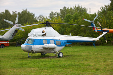 A small white helicopter with a blue stripe on the green grass.