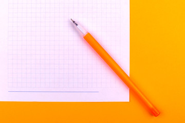 A white sheet of paper for drawings, texts, letters and notes, next to a yellow pen lies on an orange background