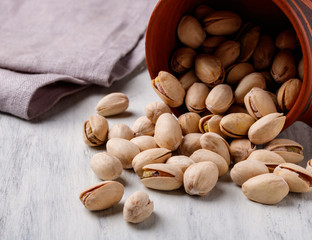 overturned cup with pistachios on a white table