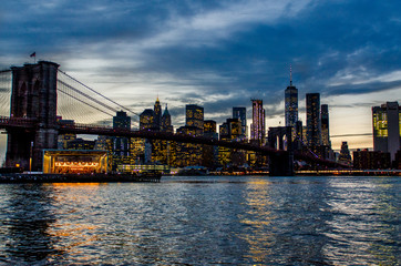 Obraz na płótnie Canvas Brooklyn Bridge during a cloudy sunset in foreground with New York City skyline in background.