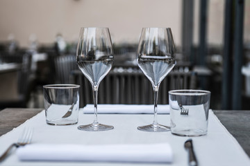 The interior of the summer restaurant. The table is served with glassware for drinks and Cutlery for two persons. Concept: preparing the table for service. Selective focus. Copy space.