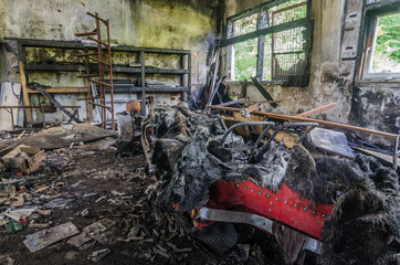roter ausgebrannter oldtimer in einem fabriksraum