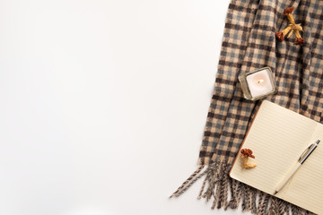 Open notebook, scarf, candle, on white background. Flat lay.
