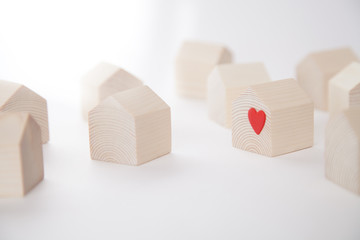 Miniature wooden house with red heart among others wooden houses