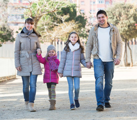 Parents with kids walking in the street .