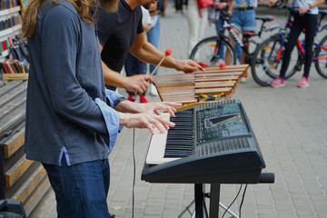  Two musicians on the street on a warm summer day. Digital piano and the traditional Xylophone. People around listen to music .    