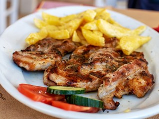 Grilled pork steaks with french fries and vegetables.