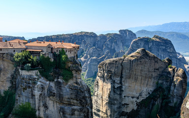 Fototapeta na wymiar Rock formations of Meteora mountains and the monastery in Greece with blue sky and green forest