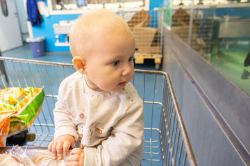 A child in a supermarket on a trolley monitors the shopping of parents.