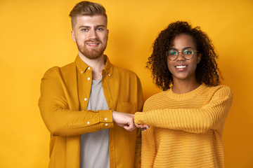 Woman with dark skin and ginger man, give fist bump, agree to work together