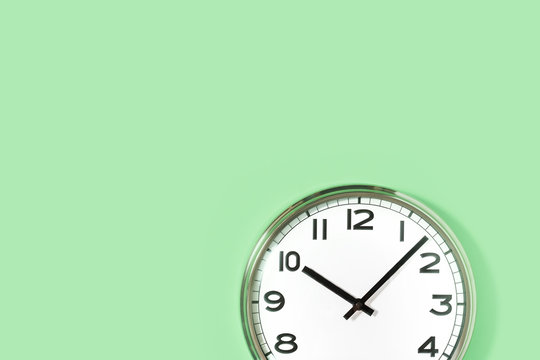 Part of analogue plain wall clock on trendy pastel mint background. ten oclock. Close up with copy space, time management concept and lunch time