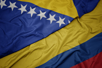 waving colorful flag of colombia and national flag of bosnia and herzegovina.