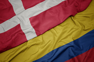 waving colorful flag of colombia and national flag of denmark.