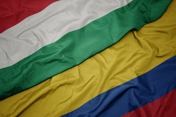 waving colorful flag of colombia and national flag of hungary.